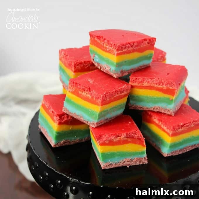 Rainbow fudge squares stacked on a black cake stand, ready to be enjoyed.