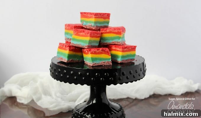 Rainbow fudge cubes stacked on a black cake stand, highlighting the contrasting colors.