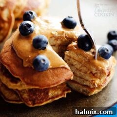 Grain-Free Banana Breakfast Cakes 5 A close-up of a fork, ready to scoop into a stack of protein-rich flourless banana pancakes, highlighted against a soft background.