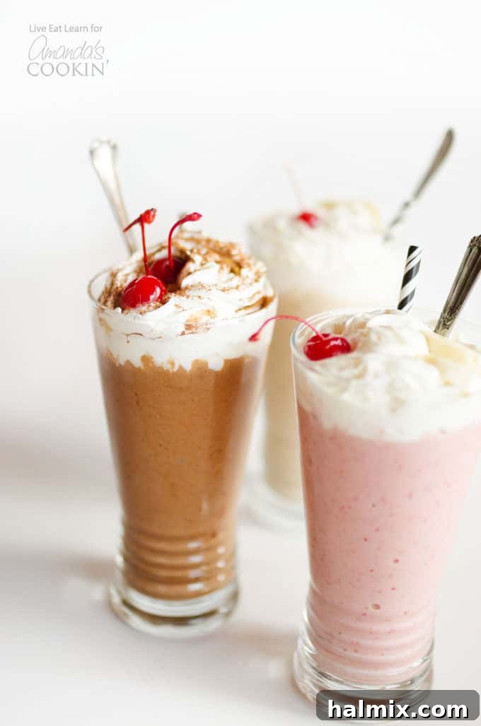 Two deliciously healthy nice cream milkshakes, one chocolate with a cherry on top, and a pink strawberry shake in the foreground, perfect for a guilt-free treat.