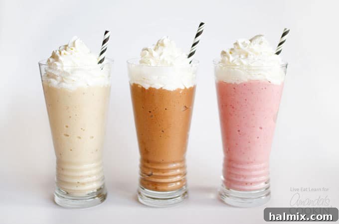 Three vibrant nice cream milkshakes: strawberry, vanilla, and chocolate, each topped with whipped cream and a unique straw, displayed on a rustic wooden surface.