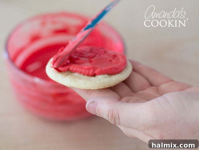 Cookie Monster and Elmo's Cookie Fun 5 Spreading vibrant red frosting evenly over a sugar cookie with a butter knife