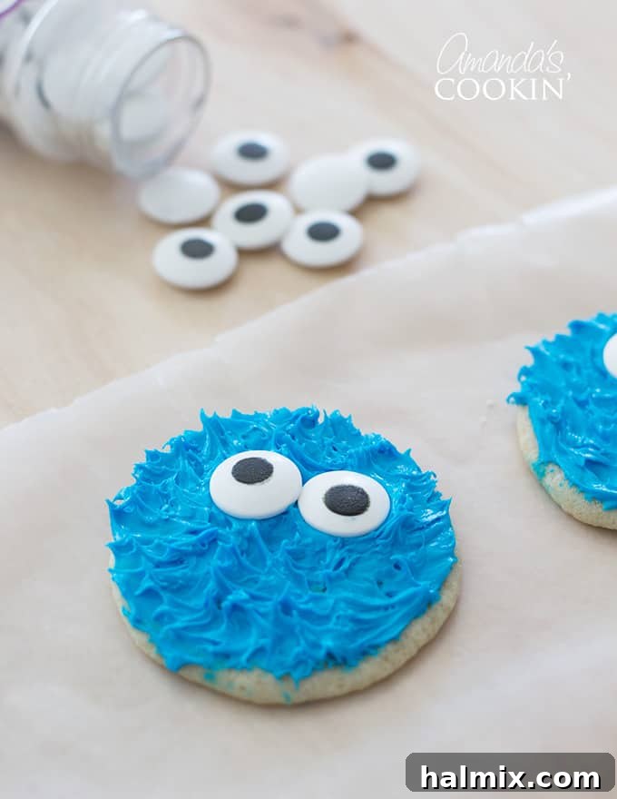 Cookie Monster and Elmo's Cookie Fun 9 Cookie Monster cookie on parchment paper with a bowl of candy eyes in the background