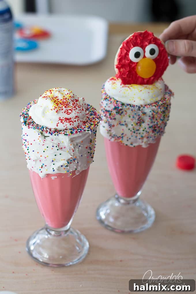 A finished Elmo Freakshake, topped with whipped cream and an Elmo cookie, showcasing the final delicious and visually appealing dessert.