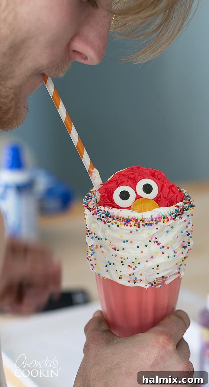 A happy boy enjoying an Elmo Freakshake with a straw, eyes wide with delight, showcasing the treat's ability to bring joy to children.