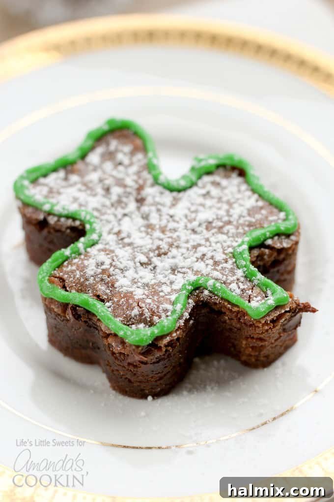 A beautifully decorated shamrock shaped brownie, adorned with white icing, sitting on a table