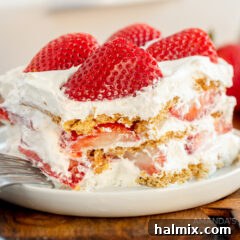 Strawberry icebox cake with a bite taken out, showing the creamy layers.