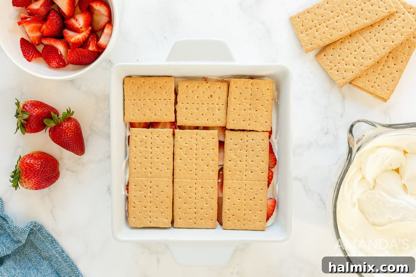 Overhead view of layered graham crackers and strawberries, halfway through the process.
