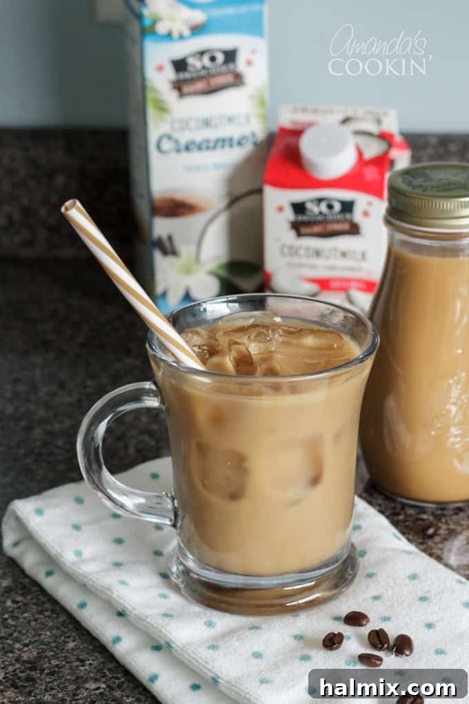 Enjoy a smooth, rich vanilla iced coffee made from homemade cold brew. This easy recipe requires minimal effort but promises maximum flavor. paper straw in a glass of cold brewed iced coffee, showcasing a rich, dark brew with ice and a sustainable straw