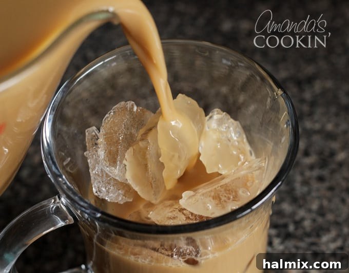 Prepare your favorite vanilla iced coffee quickly using homemade cold brew concentrate. It’s perfect for a refreshing pick-me-up. A hand pouring homemade cold brew iced coffee over a glass full of ice, demonstrating the final step before enjoyment.