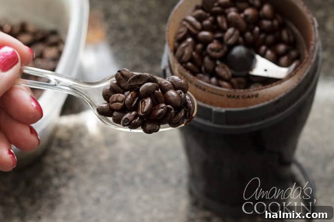 Refreshingly Smooth Cold Brew 2 Close-up of fresh, whole coffee beans being poured into a coffee grinder, emphasizing the importance of fresh grounds for optimal flavor.