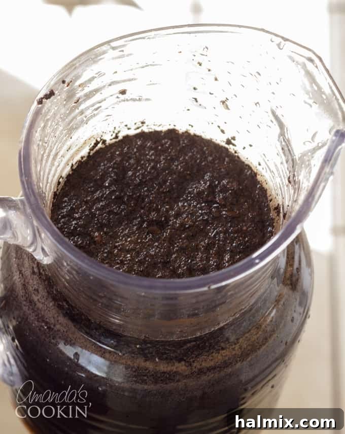 Refreshingly Smooth Cold Brew 5 A spoon actively stirring coffee grounds and water in a pitcher, demonstrating the importance of thoroughly wetting all grounds.