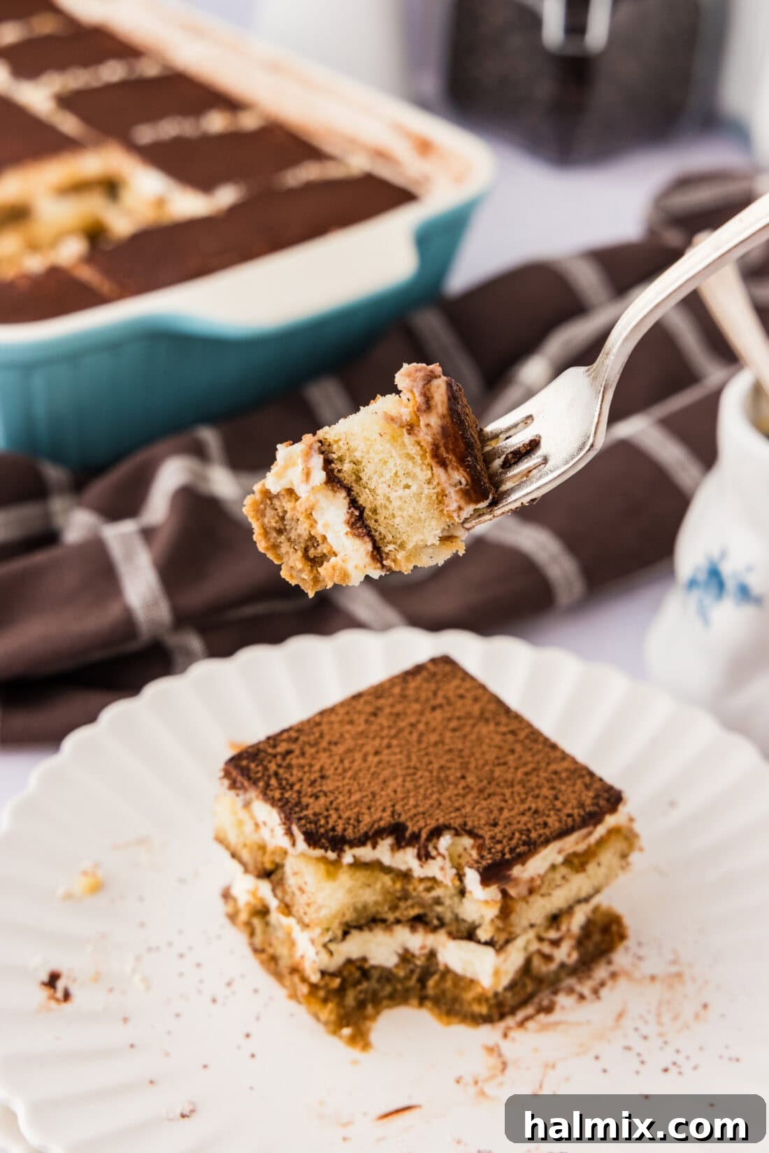 A close-up of a spoonful of Tiramisu Icebox Cake, showing the soft, creamy layers and espresso-soaked ladyfinger beneath, ready to be enjoyed.