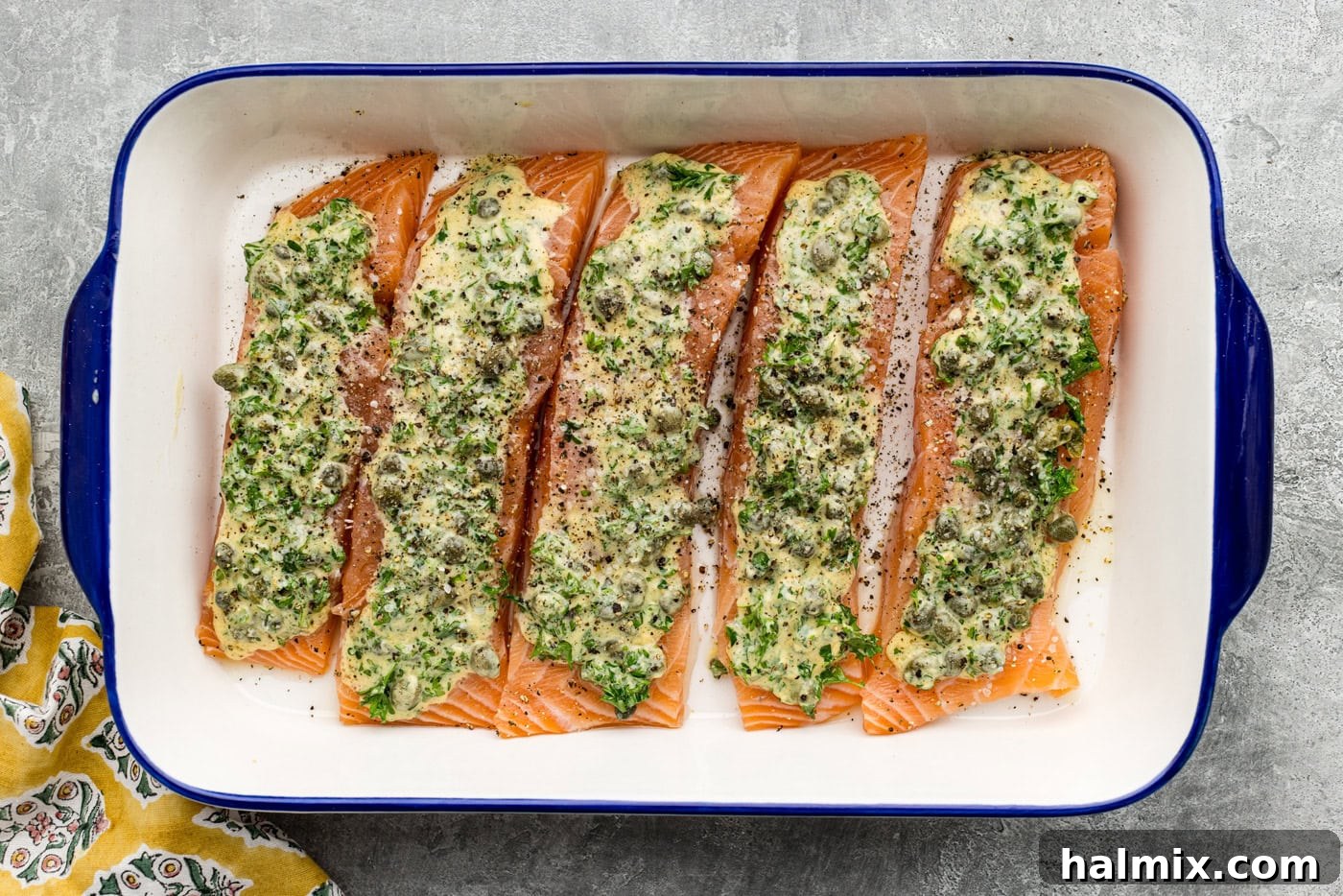 salmon filets in a baking dish topped with marinade and salt and pepper