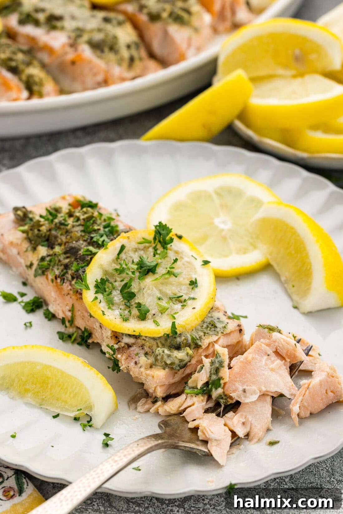 Lemon Caper Salmon filet broken apart on a plate