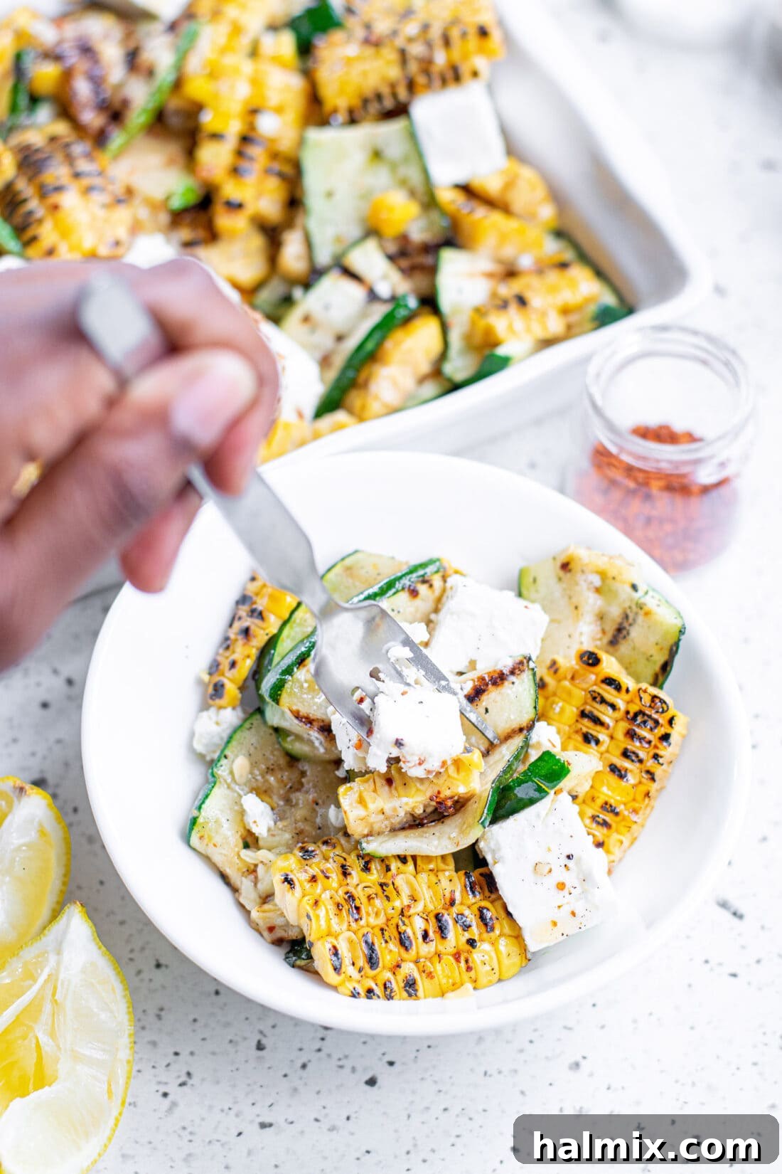 Close-up of a fork picking up some Grilled Corn & Zucchini Salad with Feta, highlighting the delicious textures