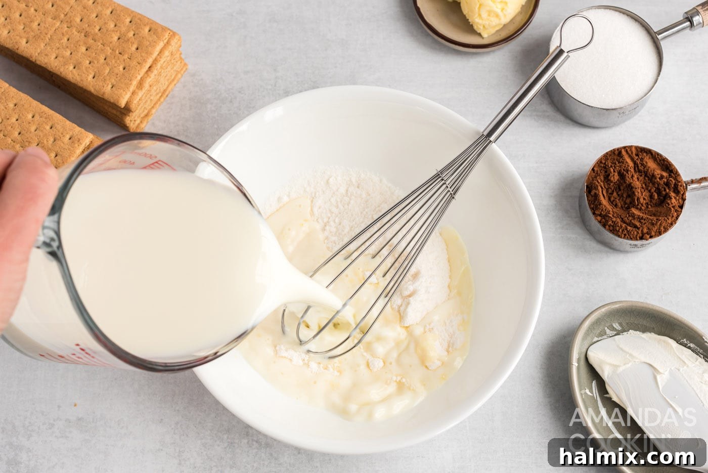 Milk being poured into dry pudding powder in a mixing bowl, ready to be whisked for the eclair cake filling.