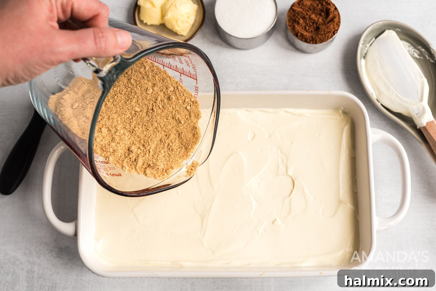 A second layer of graham crackers being carefully placed on top of the first pudding layer in the baking dish.