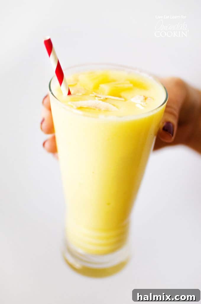 Tropical Pina Colada Smoothie in a glass with pineapple and coconut garnish