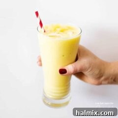 Island Getaway Pina Colada Smoothie 5 hand holding glass of pina colada smoothie recipe card image