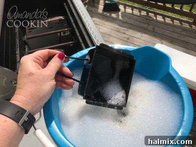 dropping grease catcher from grill into soapy water to soak