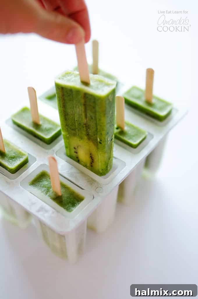 Green smoothie popsicles in a popsicle mold, showing vibrant green color and kiwi slices