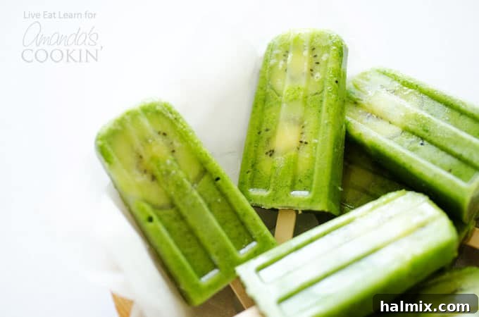 Close-up of three green smoothie popsicles, showing the smooth texture and a decorative kiwi slice