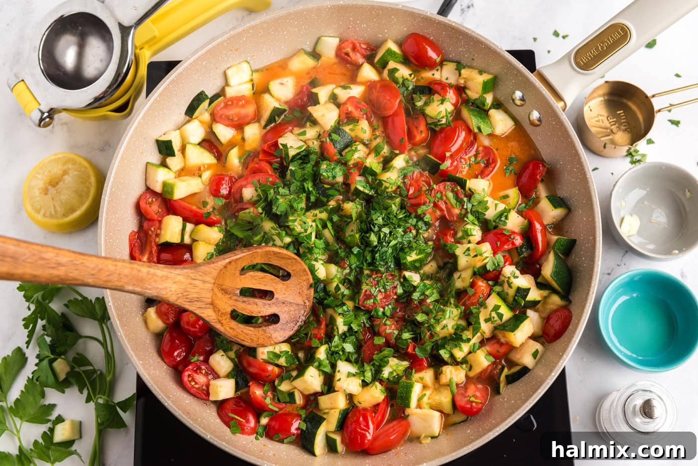 wooden spoon mixing zucchini and tomatoes with parsley in a skillet