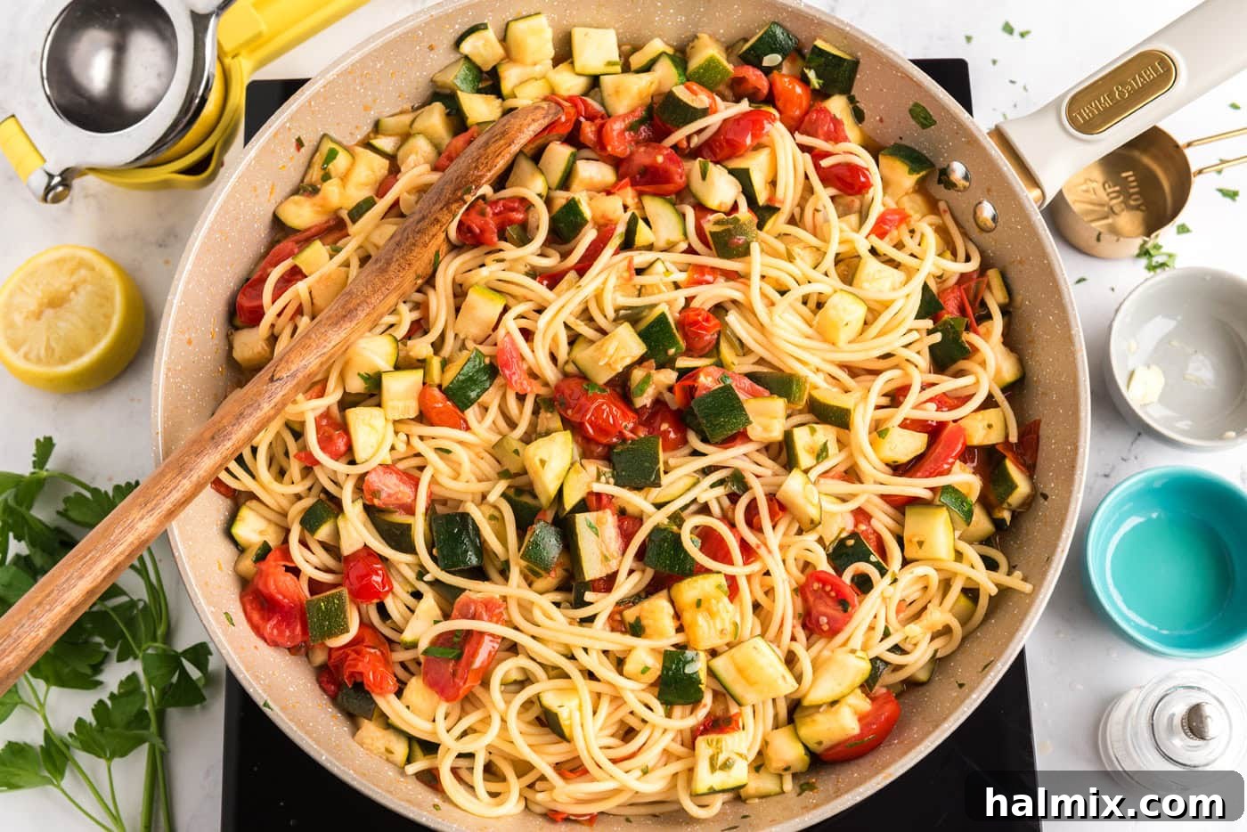 zucchini tomato pasta in a skillet with a wooden spoon