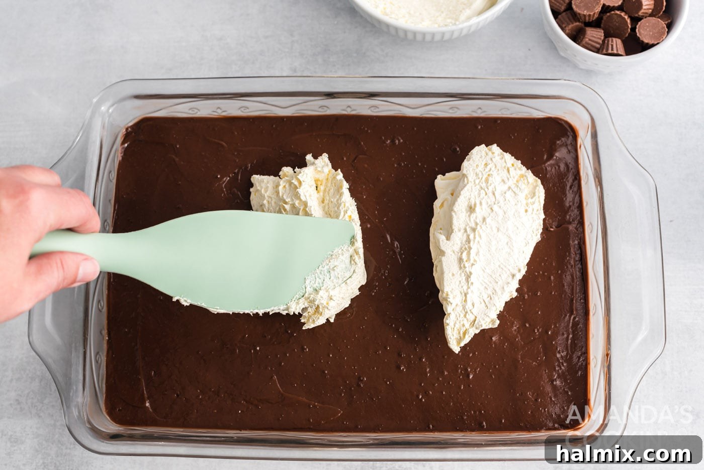 rubber spatula spreading whipped topping over chocolate pudding