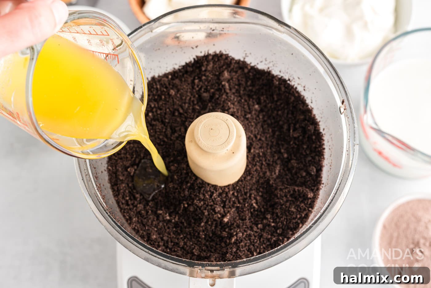 pouring melted butter into oreos crumb in a food processor