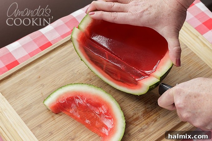 A perfectly sliced watermelon jello shot, showing the firm, vibrant gelatin set within the rind, ready to be enjoyed.