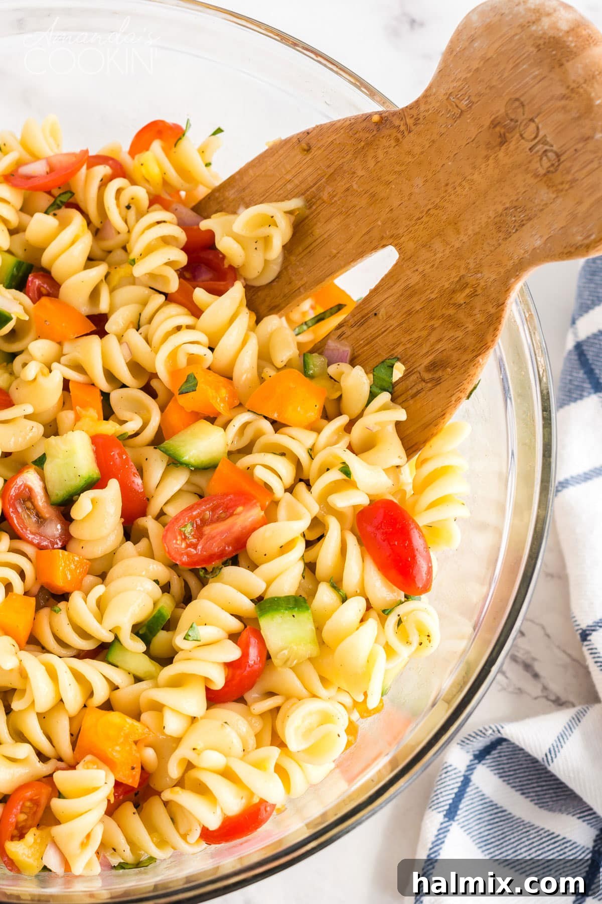 Wooden fork in bowl of summer pasta salad with fresh herbs