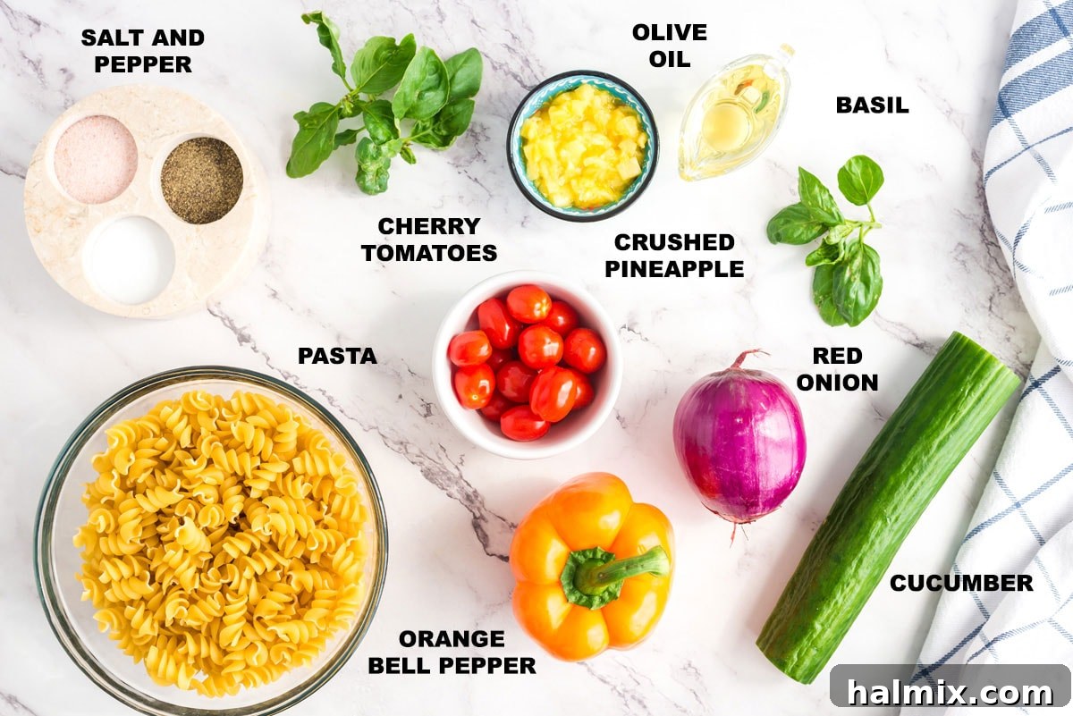 A collection of fresh ingredients for summer pasta salad including pasta, tomatoes, bell peppers, pineapple, cucumber, and red onion