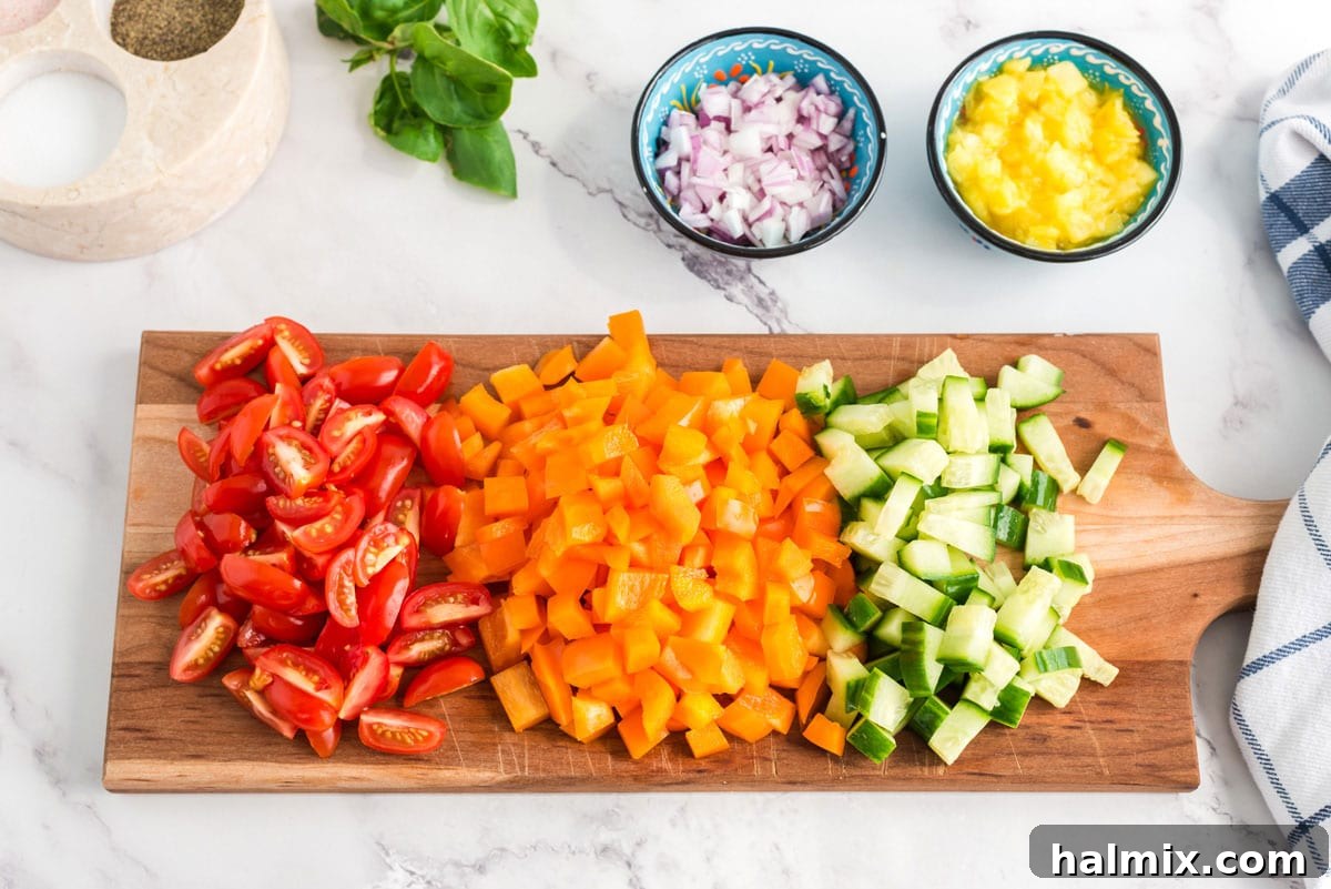Assorted chopped vegetables including bell peppers, cucumber, and red onion on a wooden cutting board
