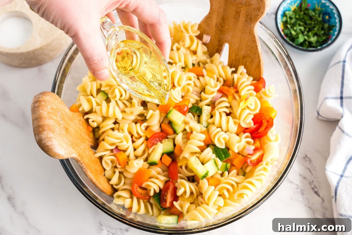 Pouring olive oil over a bowl of pasta and vegetables