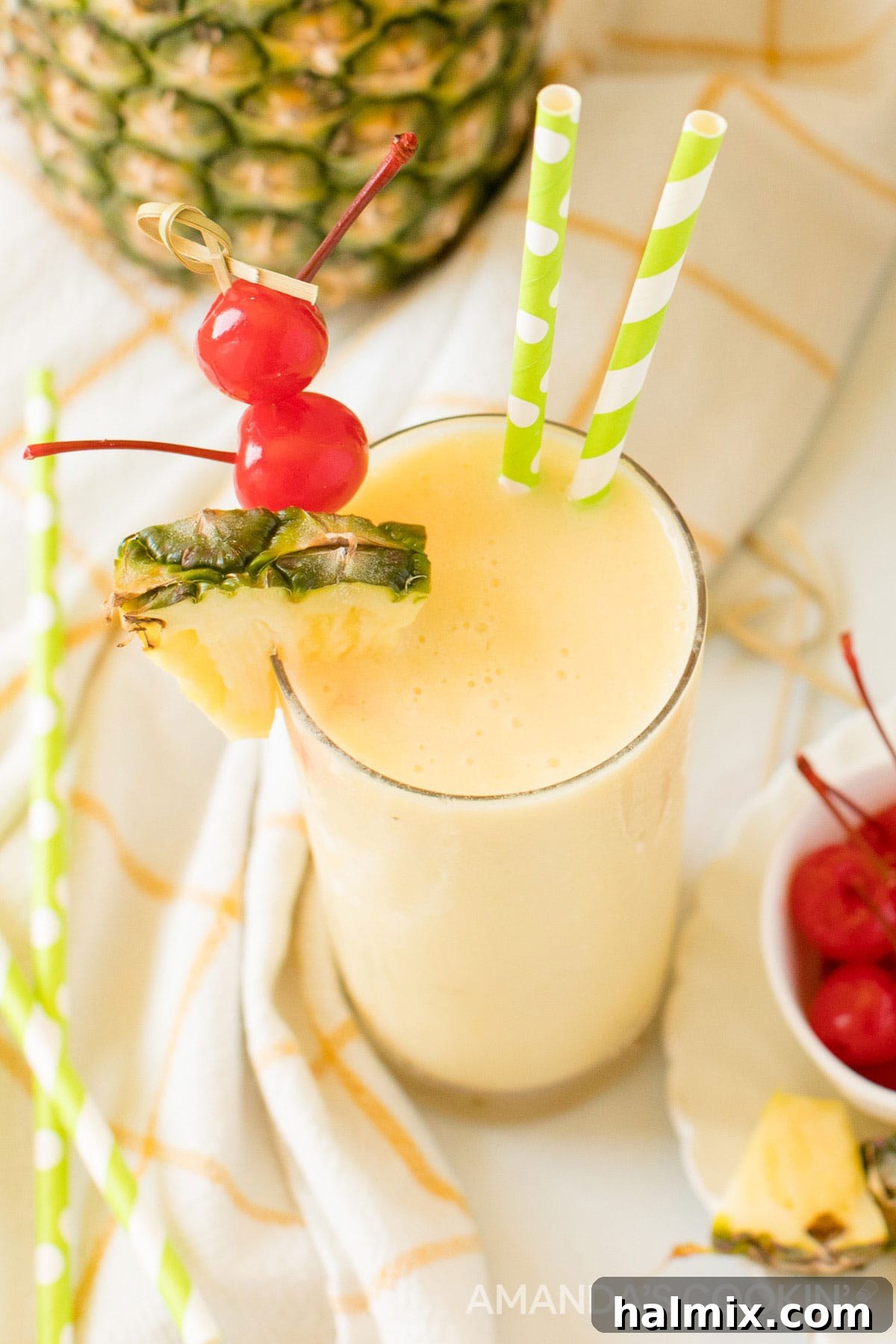 A vibrant glass of pineapple rum slush, garnished with bright red maraschino cherries, fresh pineapple wedges, and fun green and white striped straws, perfect for a hot summer day.