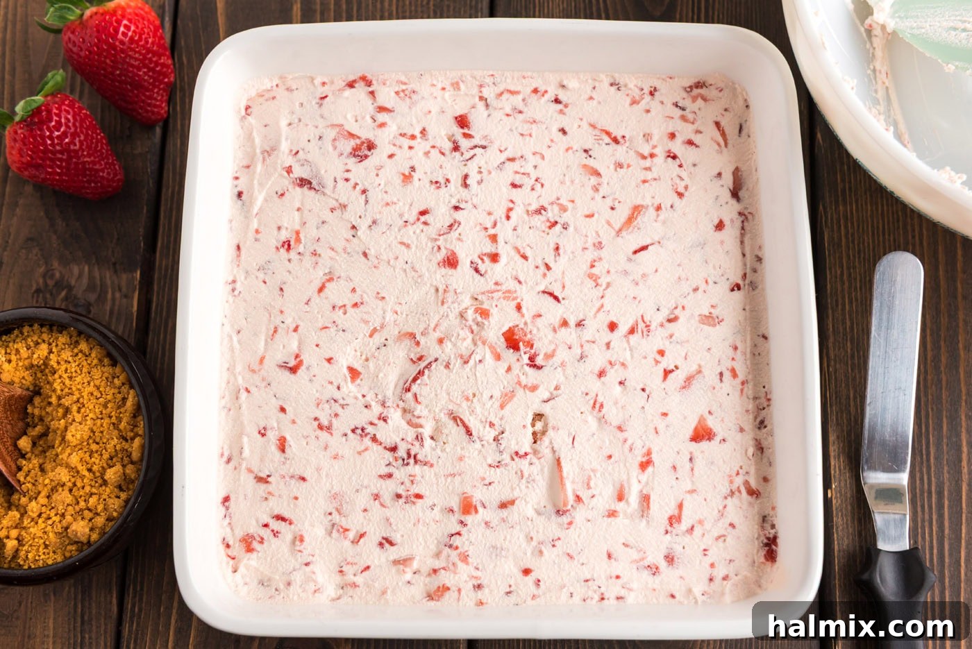 strawberry cool whip spread over cream cheese mixture in a pan