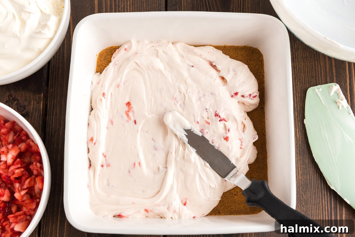 spreading strawberry cream cheese filling over graham crust