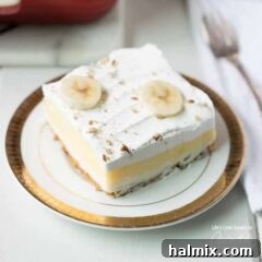 banana cream layer dessert on a plate, topped with fresh banana slices.