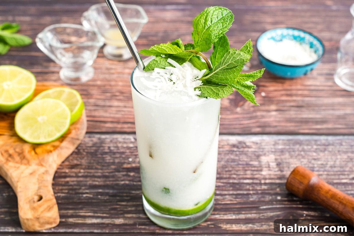A beautifully garnished glass of coconut rum mojito with fresh mint and delicate coconut flakes.