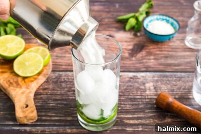 straining coconut mojito into a glass