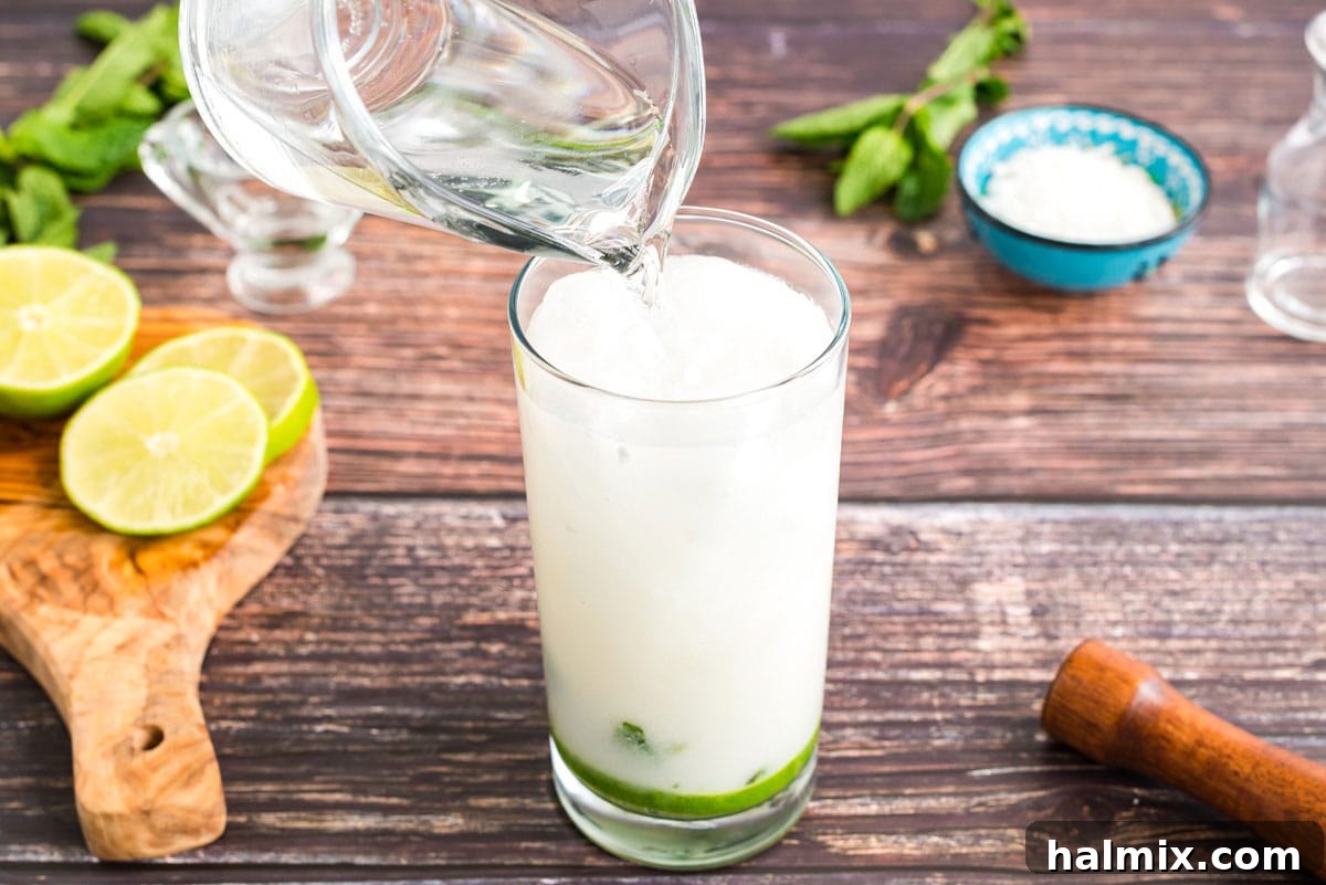 Topping off the coconut mojito with club soda, adding the perfect refreshing fizz.