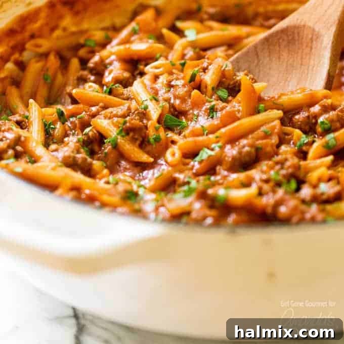 Sloppy Joe Skillet Pasta 4 A steaming pan of One Pot Sloppy Joe Pasta, with a wooden spoon resting in the rich, savory meat sauce and perfectly cooked pasta, ready to be scooped and served.