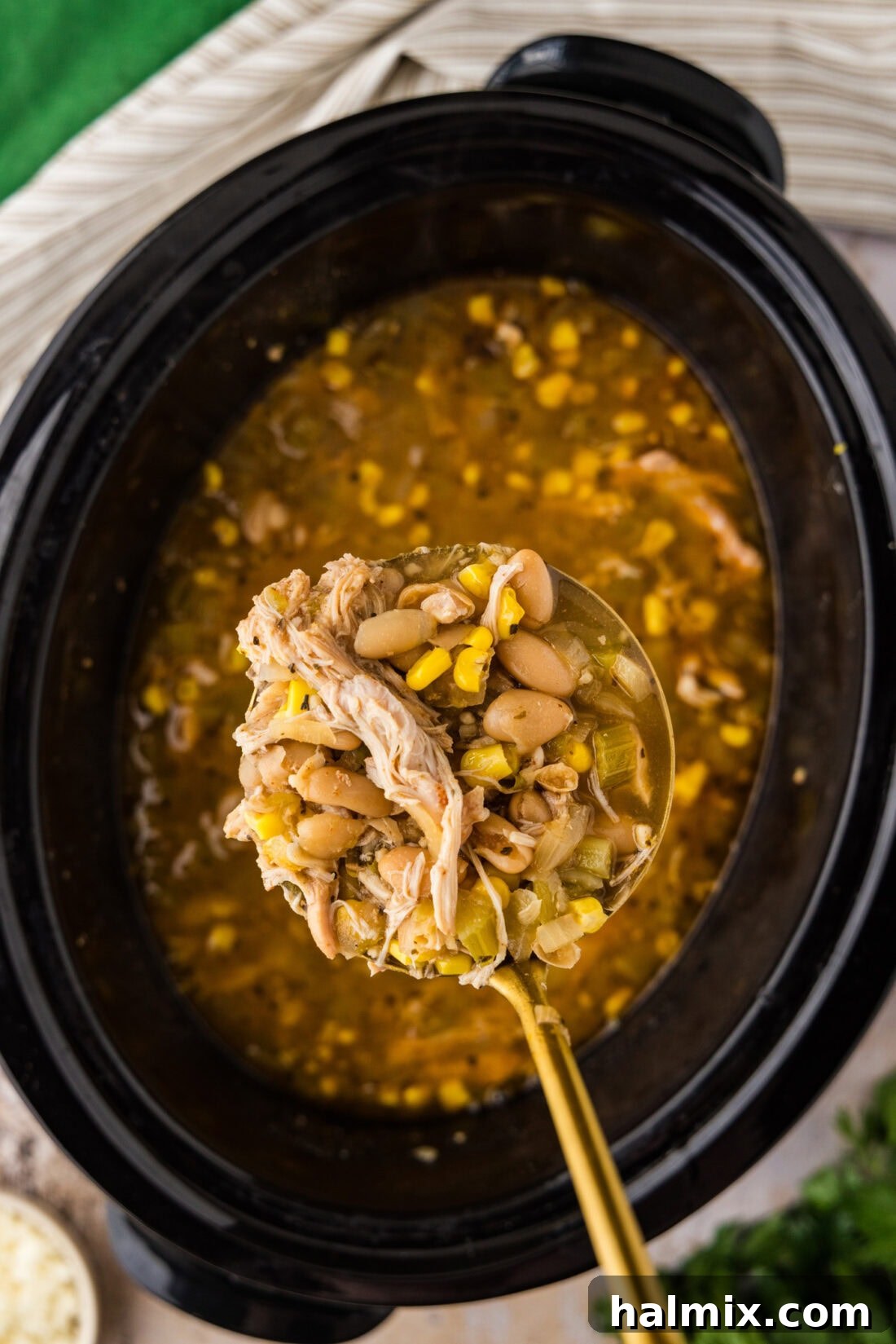 Spoon of Crockpot White Chicken Chili held above a Crockpot of Crockpot White Chicken Chili, ready to serve