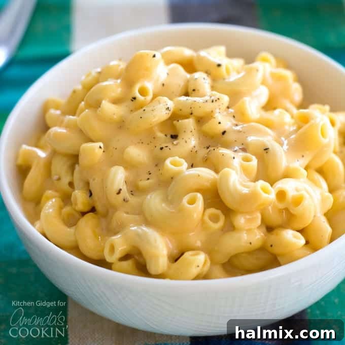 A comforting bowl of creamy mac and cheese from the slow cooker, made with a blend of rich cheeses and seasonings. Close-up of a bowl of homemade creamy macaroni and cheese, topped with fresh herbs.