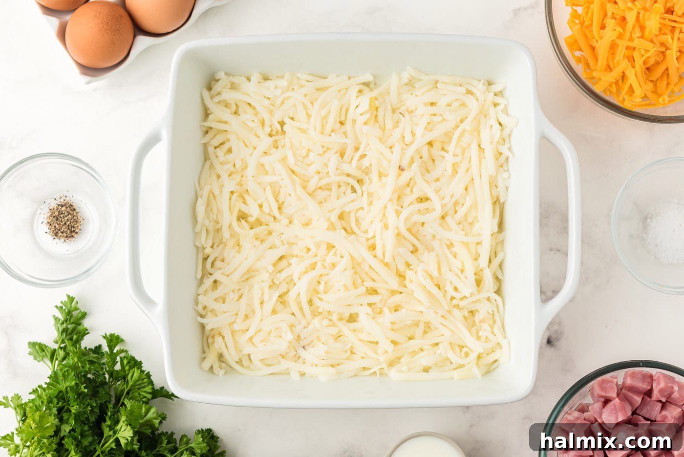 Hash browns evenly spread in the bottom of a baking dish, forming the base of the casserole.