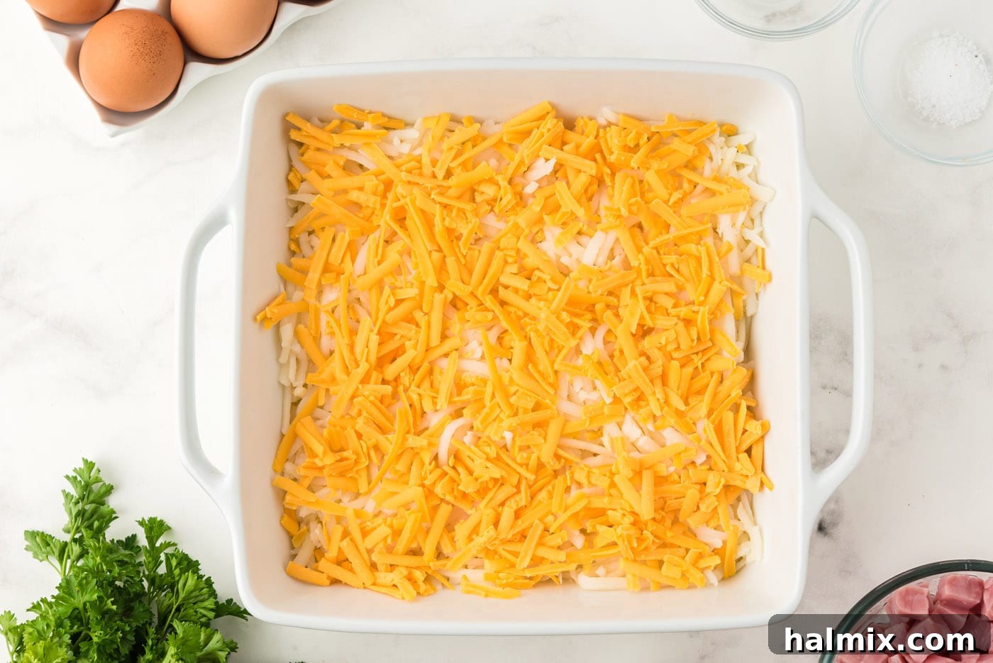 A layer of shredded cheddar cheese spread over the hash browns, ready for the next ingredient.