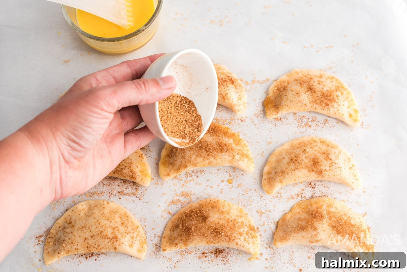 sprinkling cinnamon sugar on top of pumpkin hand pies