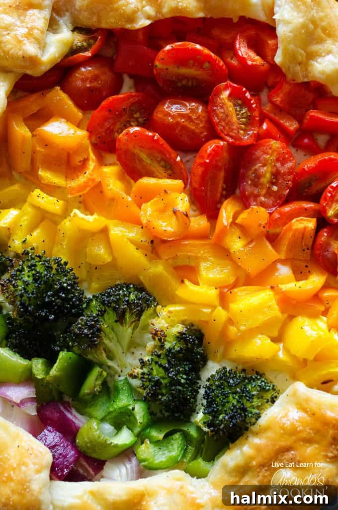 Fresh, colorful rainbow vegetables prepped and ready for baking into the savory tart. A vibrant array of chopped rainbow vegetables including bell peppers, cherry tomatoes, broccoli, and red onion, ready for the tart.